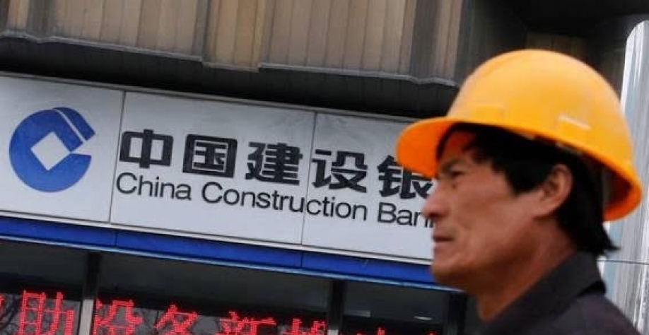 Trabalhador chinês da construção civil em frente a uma filial do CCB (Banco de Construção da China), em Pequim -  foto Kim Kyung-Hoon-Reuters